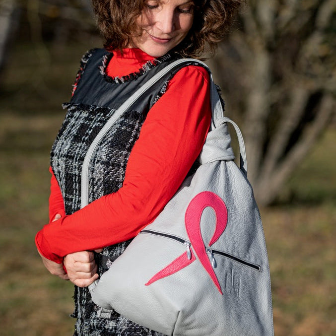 Pink Ribbon grey leather backpack wearing by a woman outside in the nature