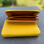 Yellow wallet on a dark surface with a blurred green background
