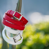 Red and white leather belts with silver buckles on a blurred natural background