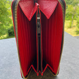 Red wallet with gold zipper on a textured surface