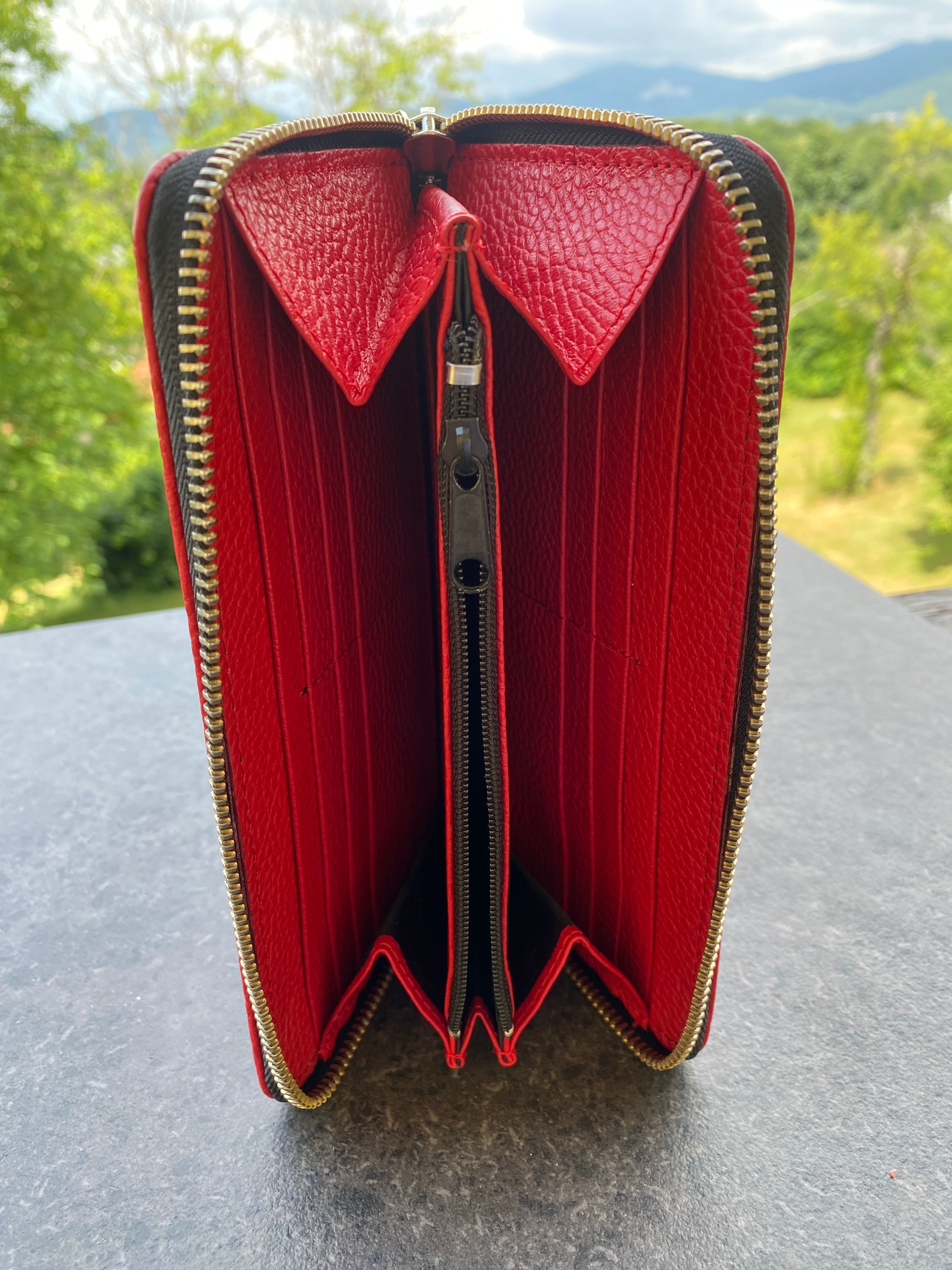 Red wallet with gold zipper on a textured surface
