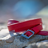 Red belt with a silver buckle on a stone surface with a blurred natural background