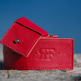 Red leather wallet on a textured surface with a blue sky background
