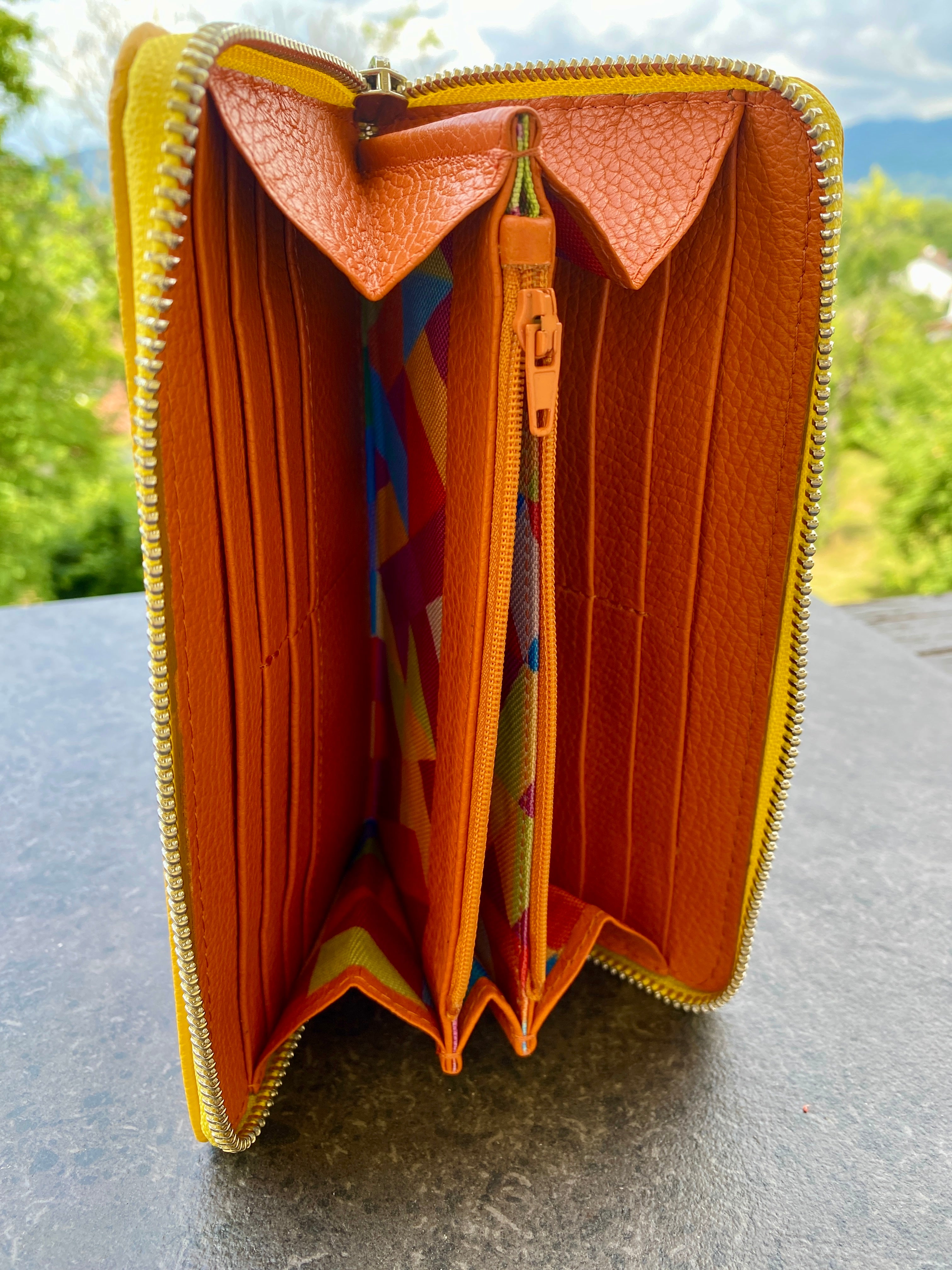 Open orange wallet with colorful interior on a gray surface