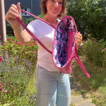 Woman holding a pink bag with a floral interior in an outdoor setting