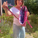 Woman holding a pink bag with a floral interior in an outdoor setting
