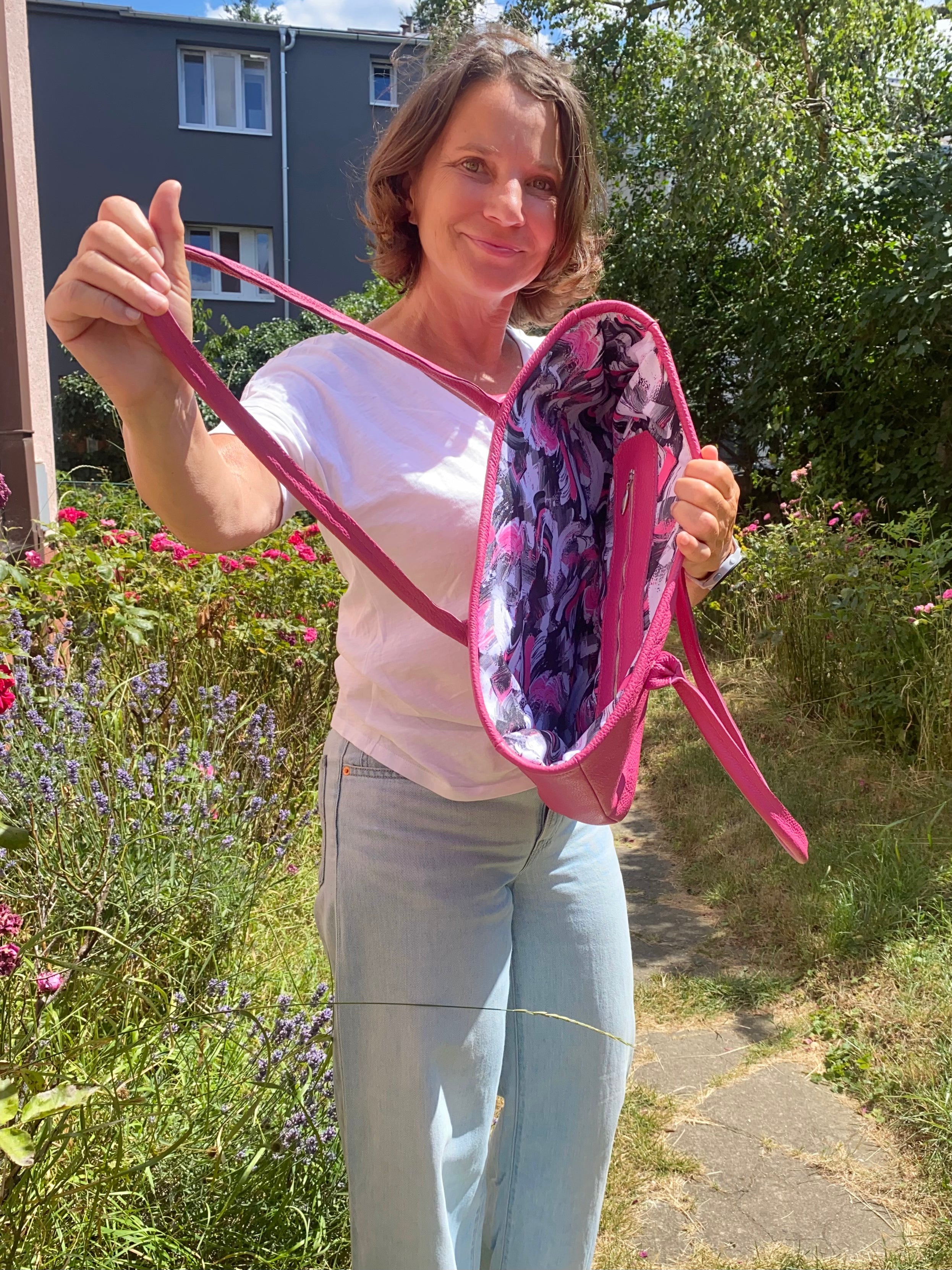 Woman holding a pink bag with a floral interior in an outdoor setting