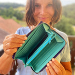 Person holding a green wallet with a scenic background