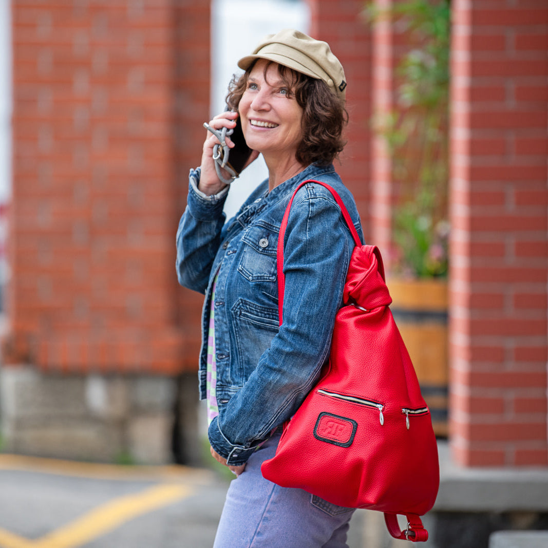 Woman with a red bag talking on a phone in front of a brick building