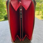 Red wallet with silver zipper on a textured surface